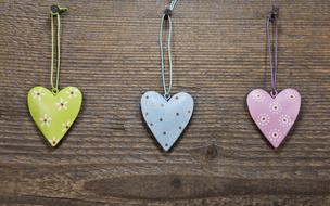 Colorful and beautiful hearts with flowers, hanging on the screws in the wooden wall