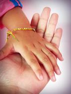 Adult holding cute hand of the baby, with colorful bracelet