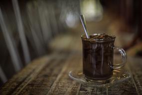 Beautiful hot chocolate drink in the glass with spoon, on the glass saucer