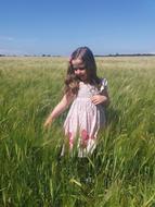 Cute girl, among the colorful and beautiful plants on the field, under the blue sky with clouds