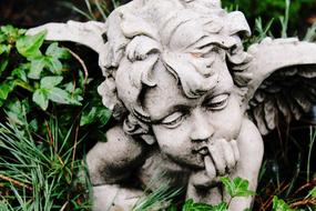 Sculpture of the angel, among the green plants