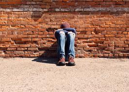 Young Person Sitting at old red brick wall