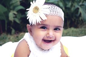 baby posing with a white flower on her head