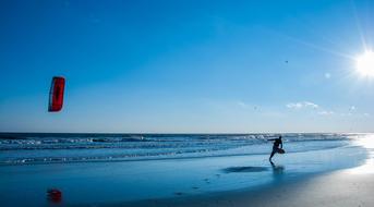 man with Kite and board walks on Beach