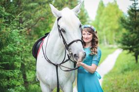 woman in turquoise dress with white horse