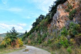 Beautiful landscape of the mountain road with colorful plants, under the blue sky with white clouds, in the autumn