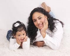 Smiling mother and daughter laying on the soft surface