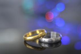 Close-up of the colorful, shiny, metal wedding rings, with reflections, at background with colorful bokeh lights