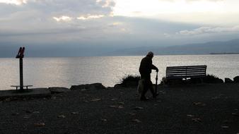 elderly man on the shore near the lake at sunrise