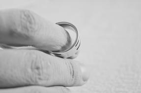 Black and white photo with the close-up of the person's hand with shiny wedding ring