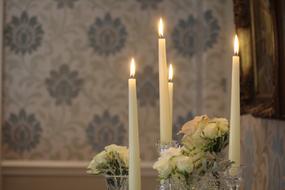 Close-up of the beautiful candles and white flowers in vases, on the wedding table