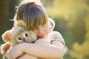 girl hugs teddy bear