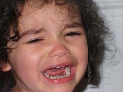 Portrait of the crying child girl with curly hair