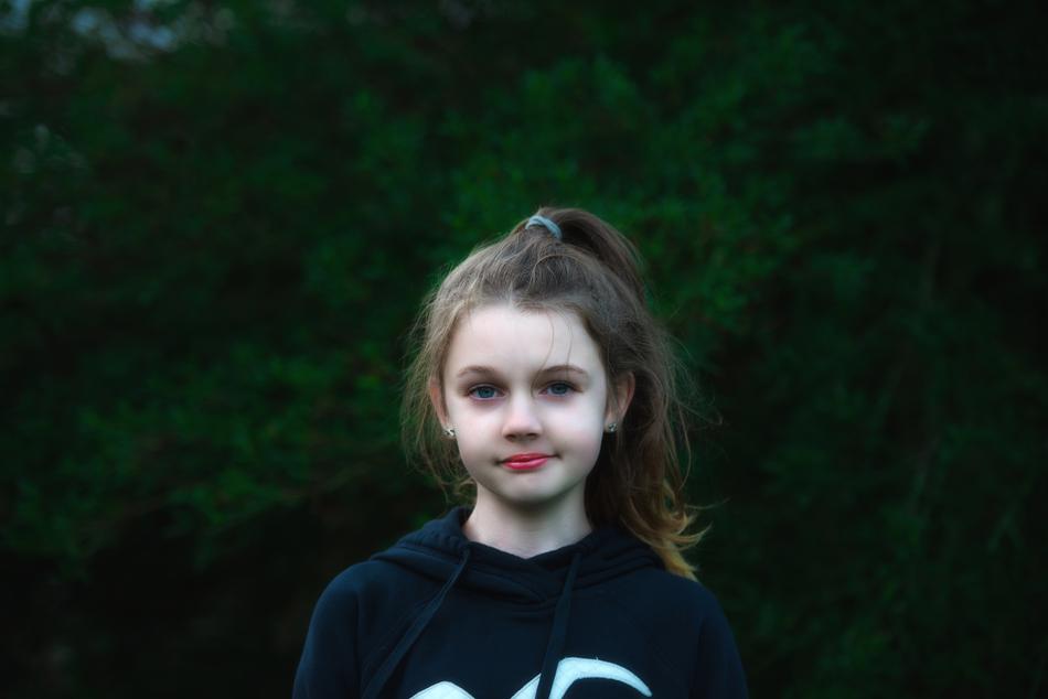 photo of a girl in a sweatshirt on a background of green tree