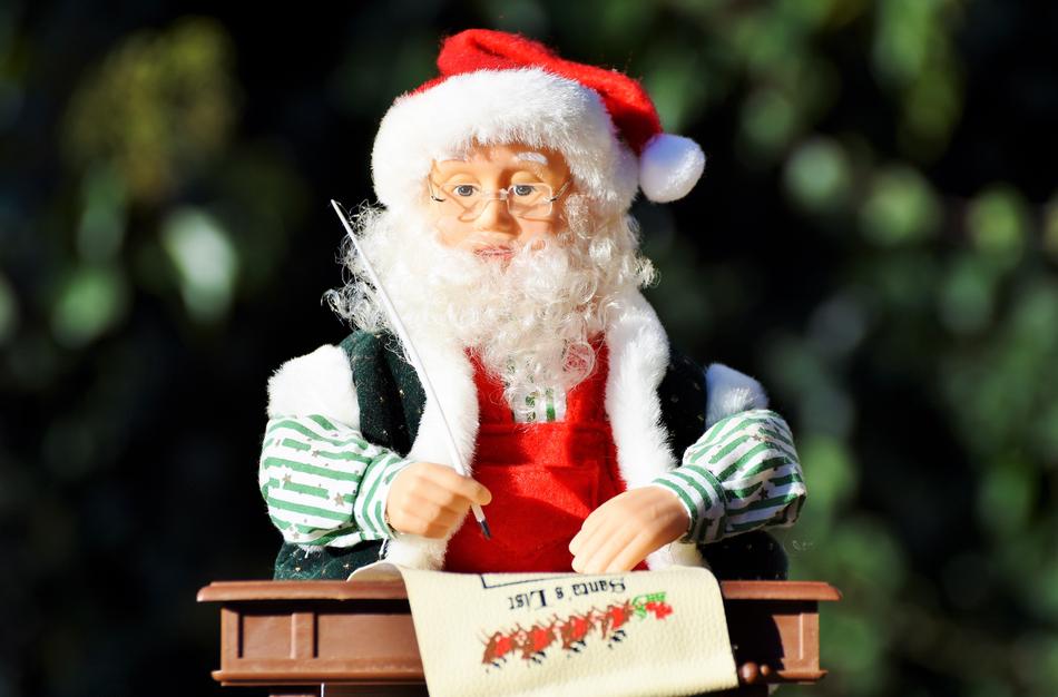 Figure of the beautiful and colorful Santa Claus, writing on the paper, at blurred background