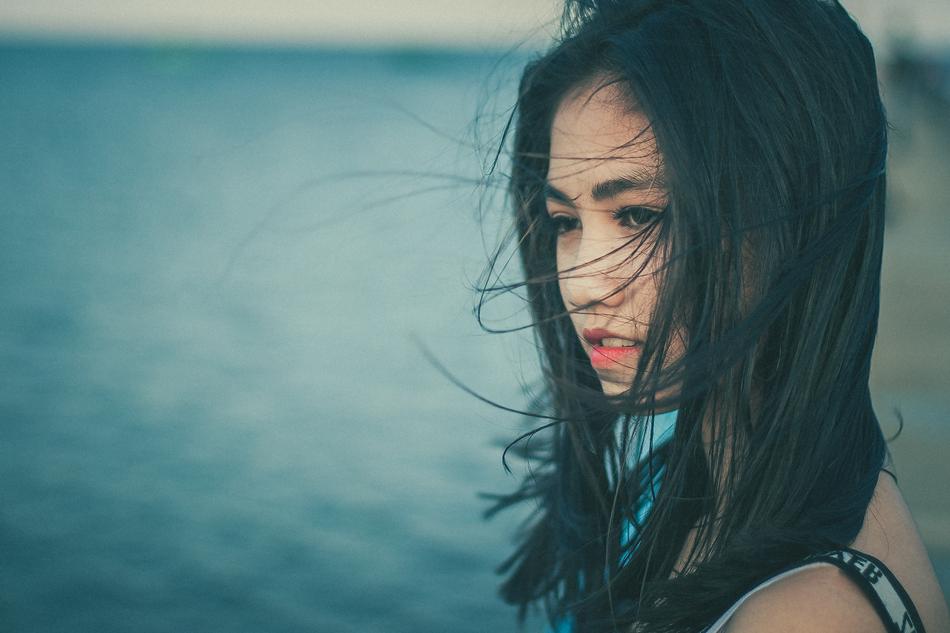 brunette with sad eyes near the water on a blurred background
