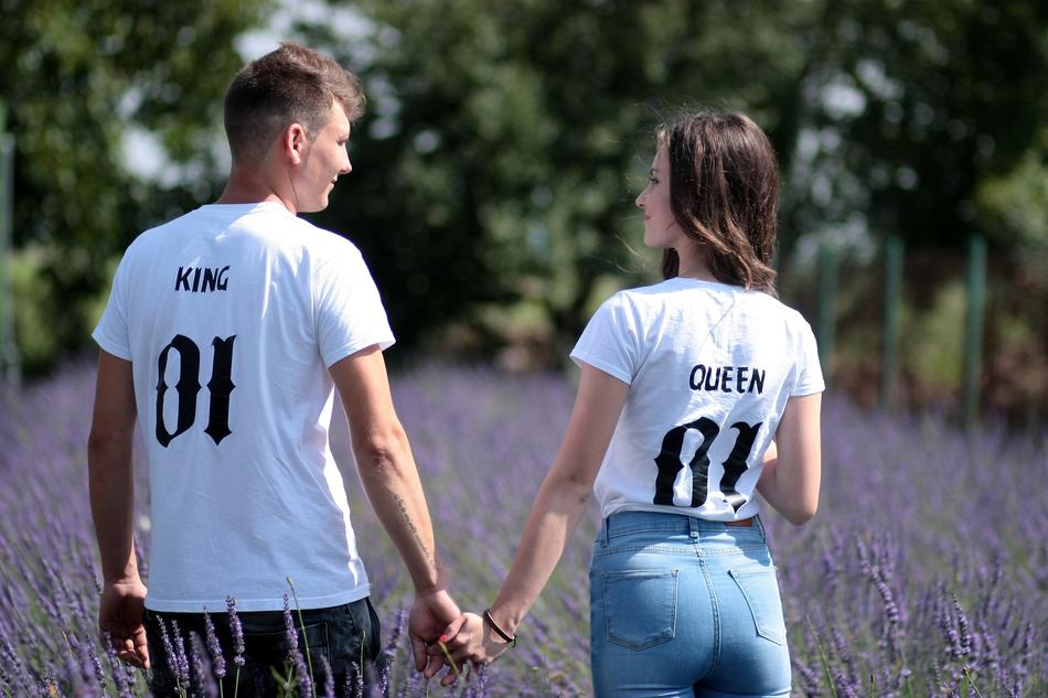 Back view of the couple in t-shirts with 'King' and 'Queen' signs, among the beautiful lavender field