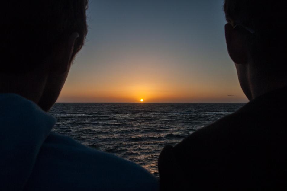 silhouettes of people on the background of sunset near the ocean