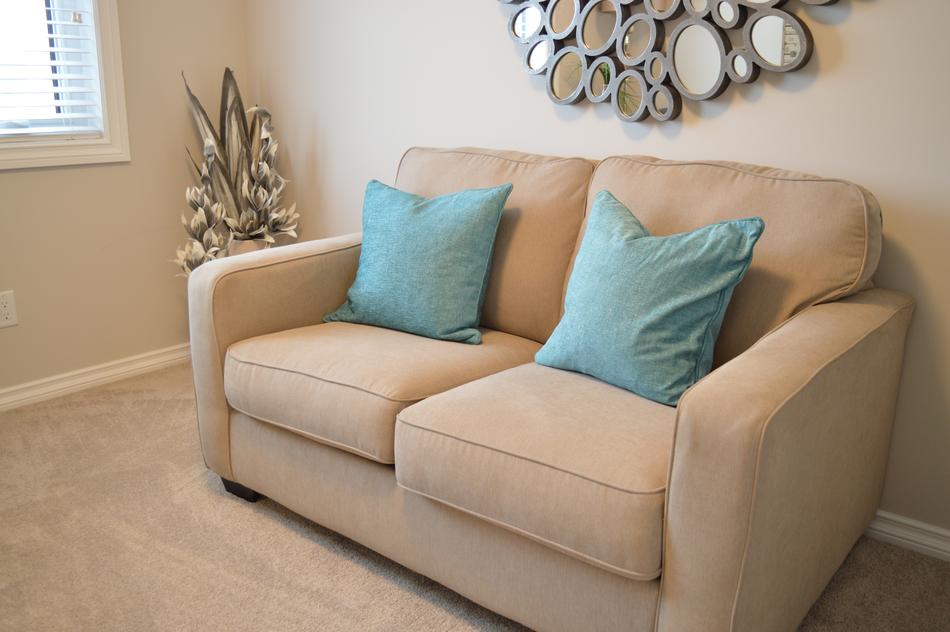 Beautiful, beige couch with turquoise pillows, in the room with decorations