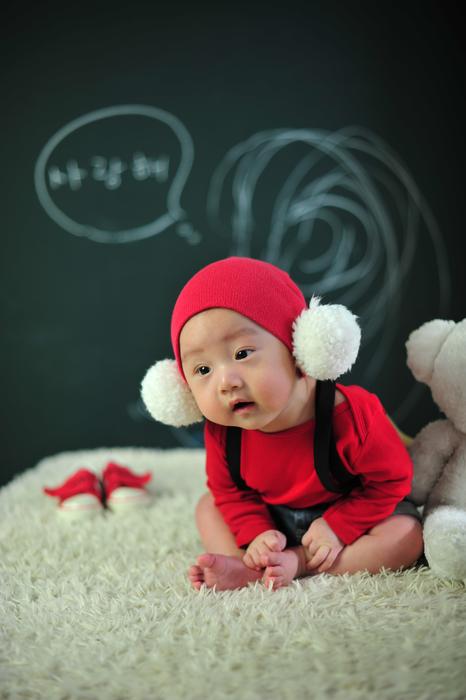 Cute child in red and white clothing, on the soft surface