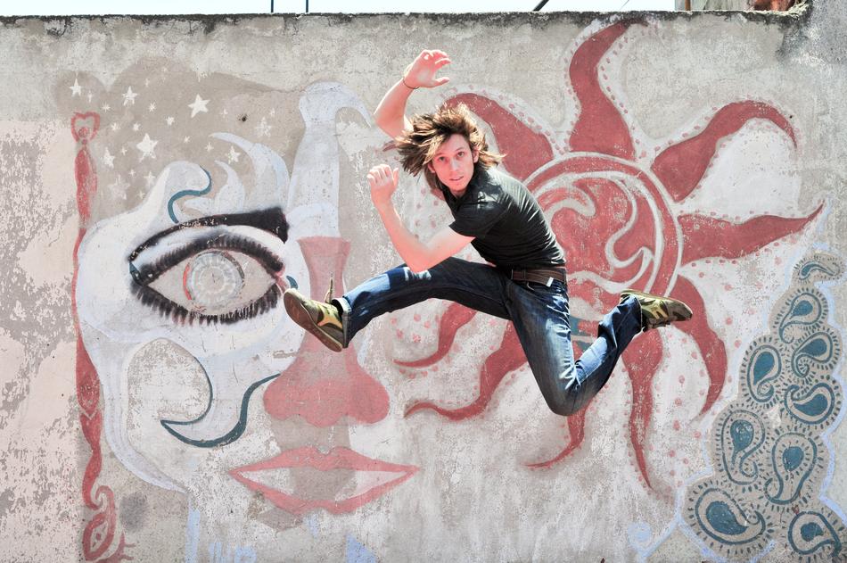 Male jumping near the wall with colorful graffiti with shapes