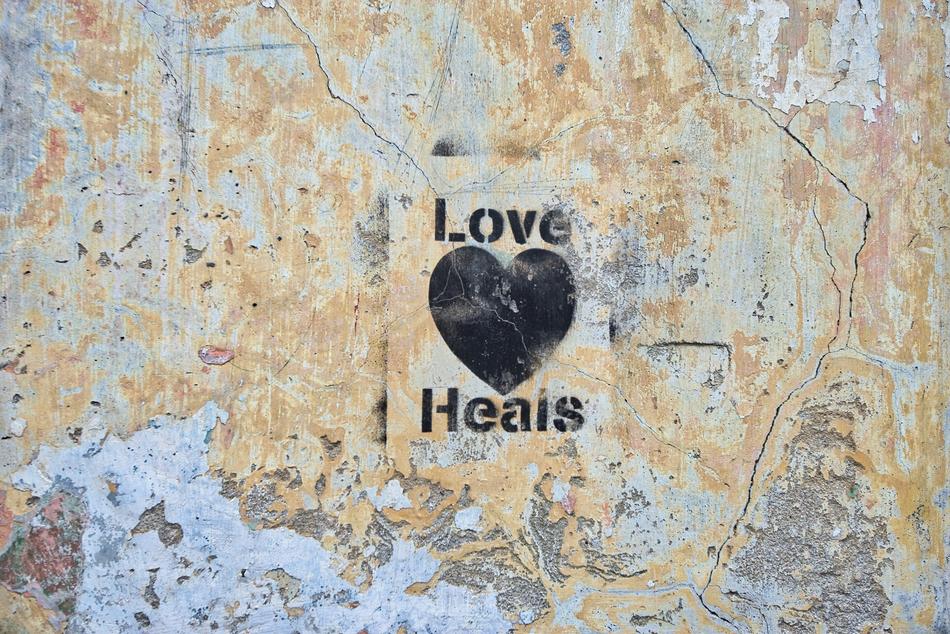 Black 'Love Heals' sign with heart, on the colorful heart