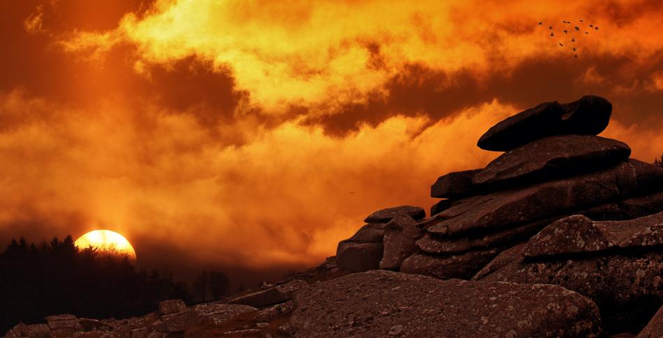 Beautiful landscape with the rocks, near the trees, at beautiful orange sunrise, among the clouds