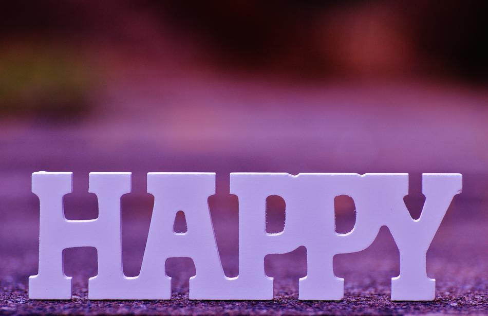 White 'HAPPY' sign on the ground, at colorful, blurred background