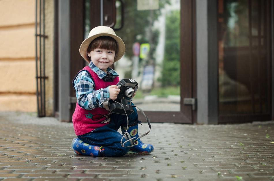 boy in a hat with a netro camera on the street