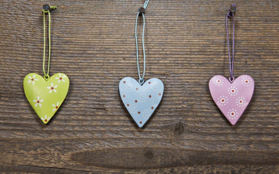 Colorful and beautiful hearts with flowers, hanging on the screws in the wooden wall