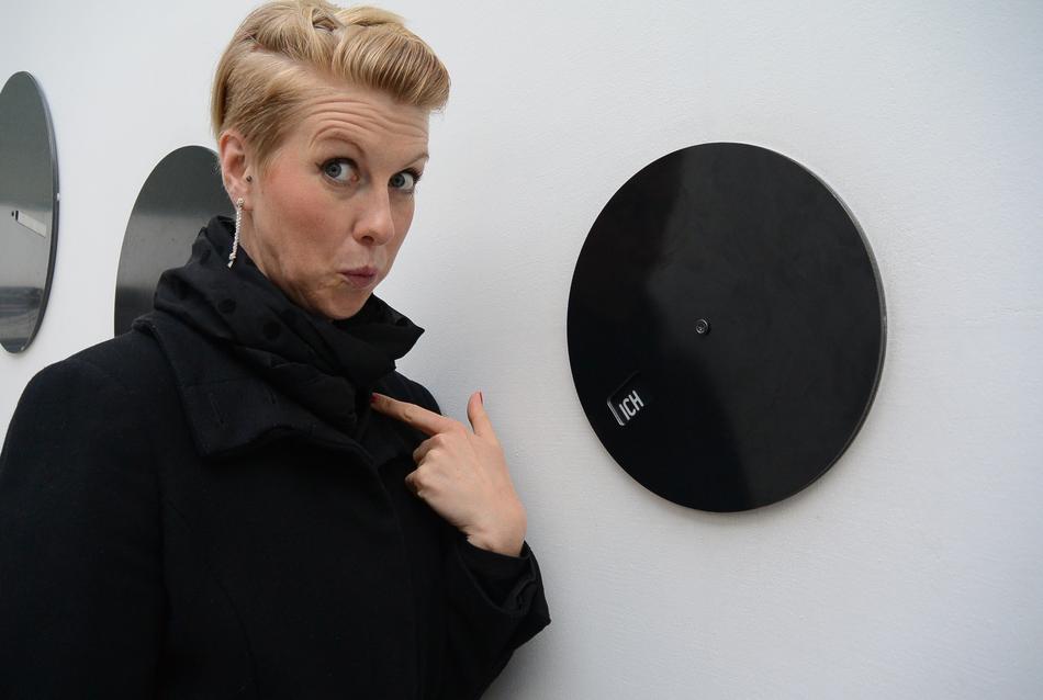 Blonde woman, near the shiny, black and white circles, on the white wall, on the Biennale