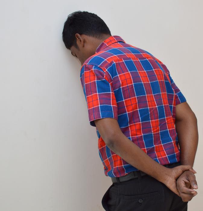 Frustrated, black-skinned guy in colorful shirt, laying on the wall