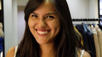 Portrait of the smiling girl, at background with hanging clothes