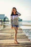 a girl in a striped sweater stands on the pier