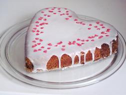 Beautiful heart cake with cream and pink hearts, on the glass plate