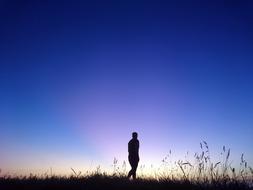 silhouette of a man on a field against a blue sky