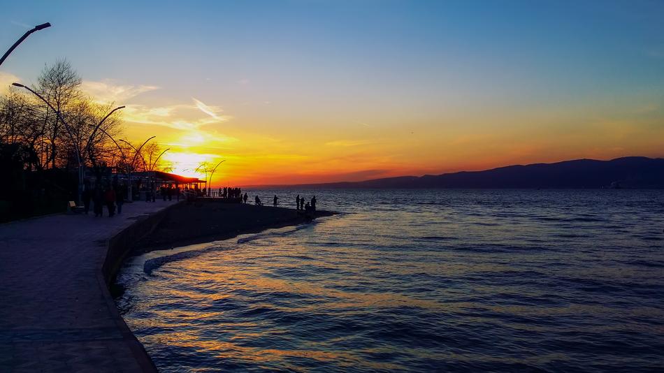 silhouettes of fishermen on the seashore at sunset in iskele, Turkey