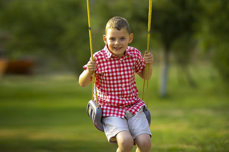 child Boy Swinging in garden at summer