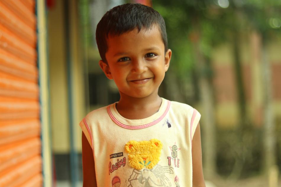 smiling boy standing against the wall of the house