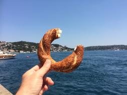 Turkish Coiled Tahini Bun in female hand at sea coast, turkey, istanbul