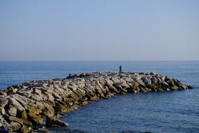 Man Fishing on stone coast view