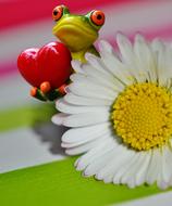 Figurine of frog sitting with a heart at a flower