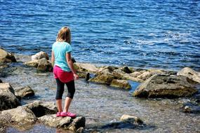 girl standing on rock by the sea