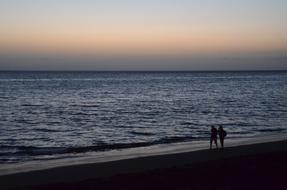 people walking on the beach in the evening