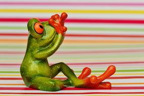 Figurine of a lonely frog on a colored background