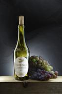 a bottle of white wine and grapes on the table