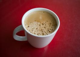 coffee with foam in a cup on a red table