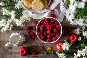 Raspberry, cookies and flowers on wooden table