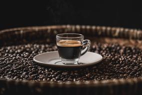 cup of espresso on a tray with coffee grains