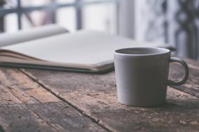 open magazine and white cup on table close-up on blurred background